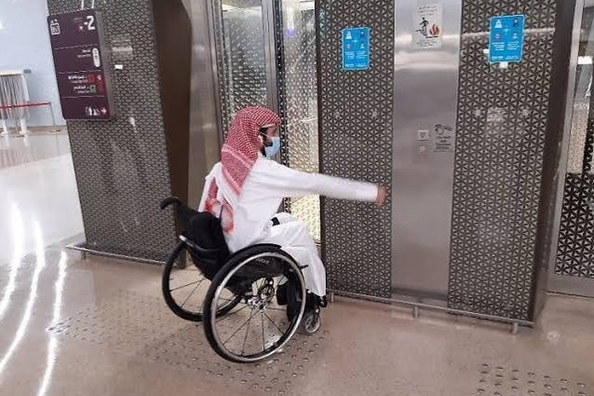 Un homme en fauteuil roulant appuie sur le bouton de l'ascenseur dans une station du métro de Doha
