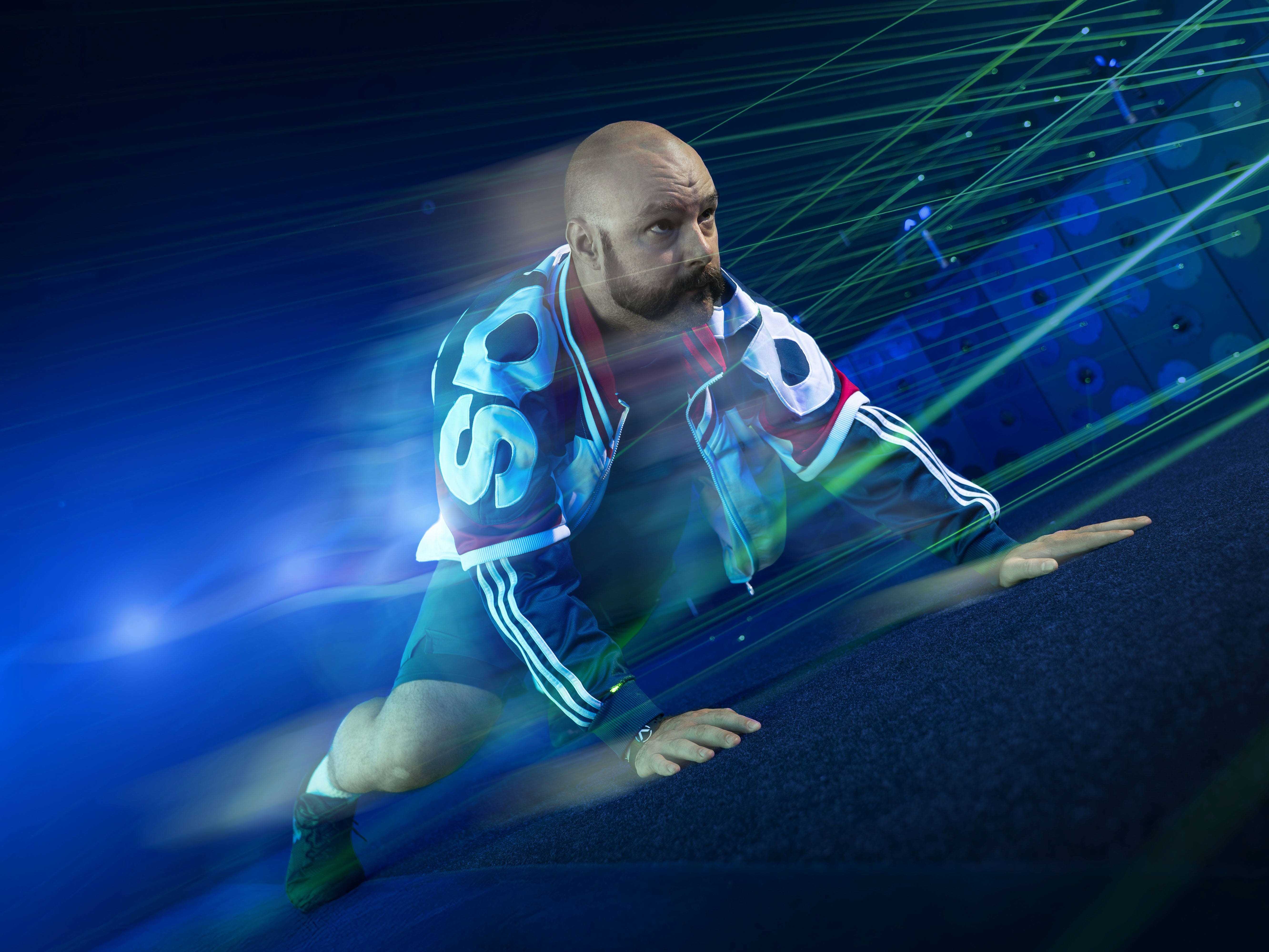 A person in a futuristic outfit is performing a dynamic pose amidst vibrant blue and green light effects.