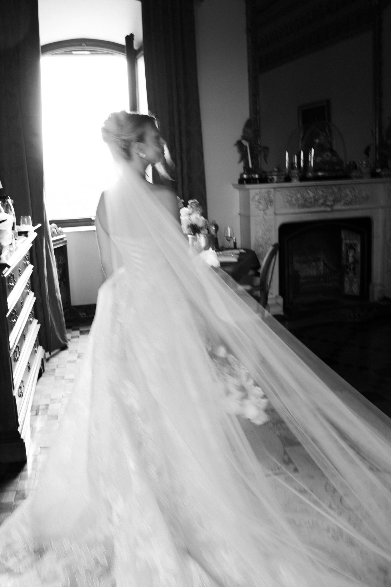 Sposa con velo lungo davanti alla finestra del castello di Tabiano, luce naturale sull'abito, reportage matrimoniale Fotolize