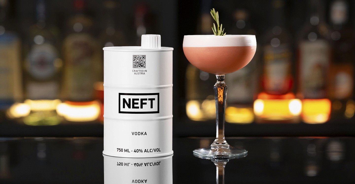 A NEFT Barrel and a glass of Vodka Pomegranate Whip on a bar counter.