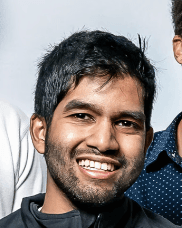 A smiling young man with dark hair and a beard, representing the diverse talent behind PointOne's digital product solutions.