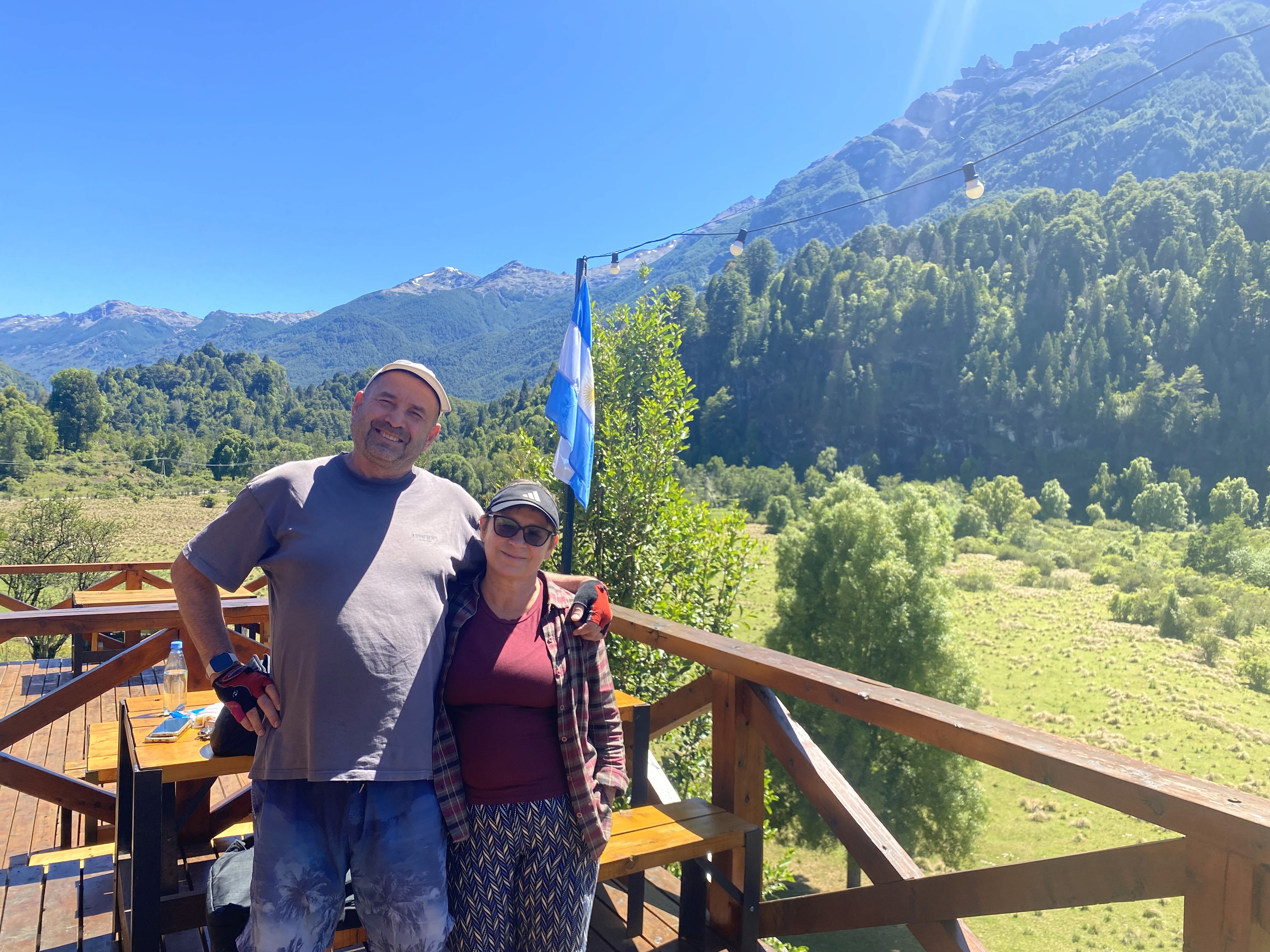Mujer sentada sobre un tronco frente a una cascada doble en un bosque frondoso de Argentina.