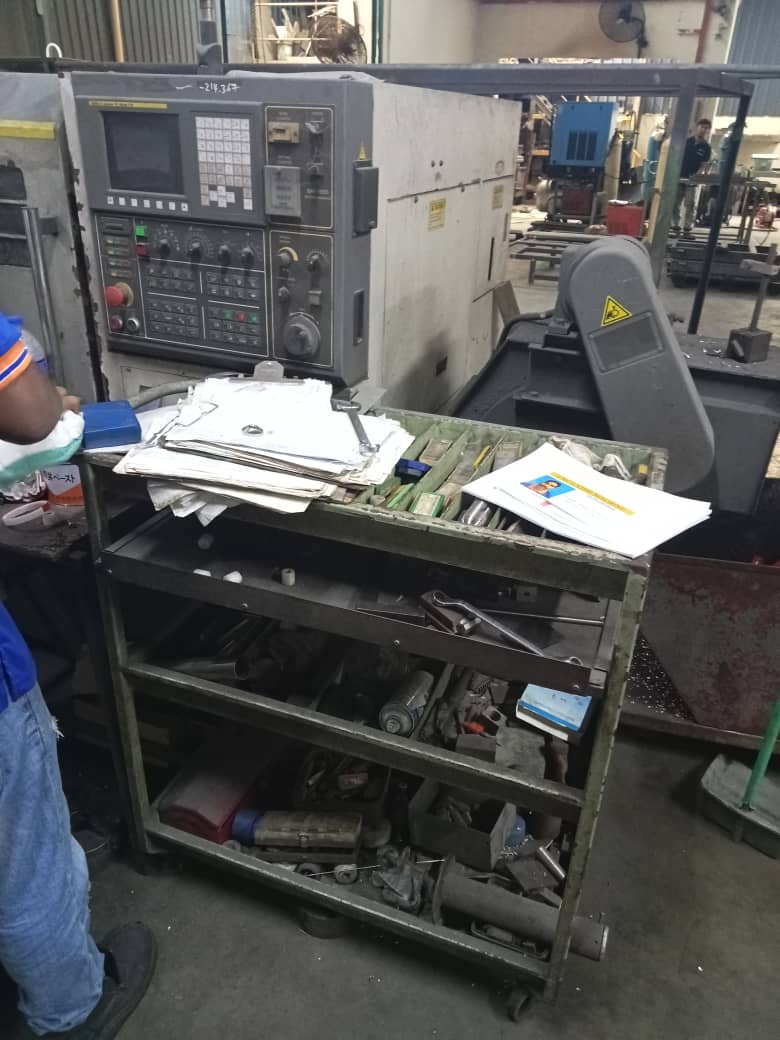 Before 5S implementation: Close-up of tools and documents cluttered around the machining station.