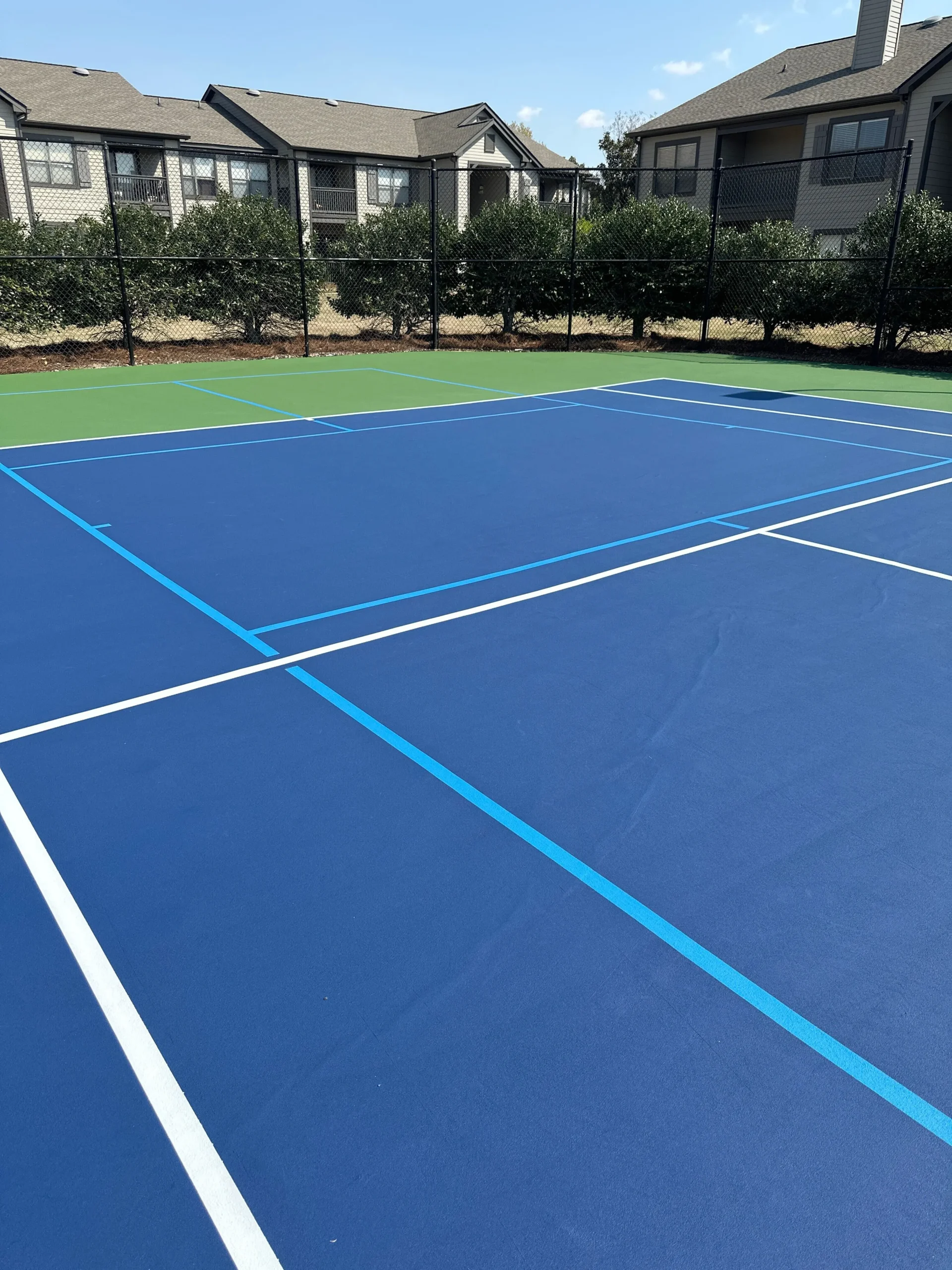 Freshly resurfaced tennis court showing blue in-bounds and green out-of-bounds color system at Weston Ranch in Madison, AL