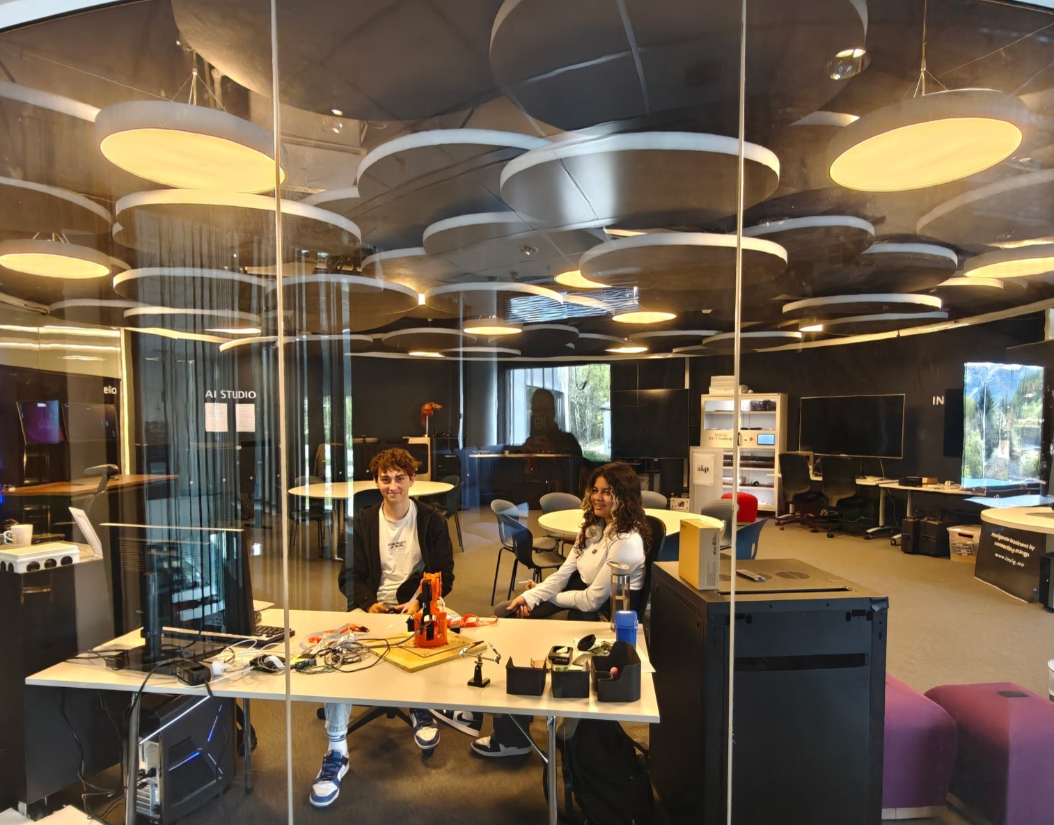 A person wearing a virtual reality headset stands in front of multiple screens, engaged in a digital experience.