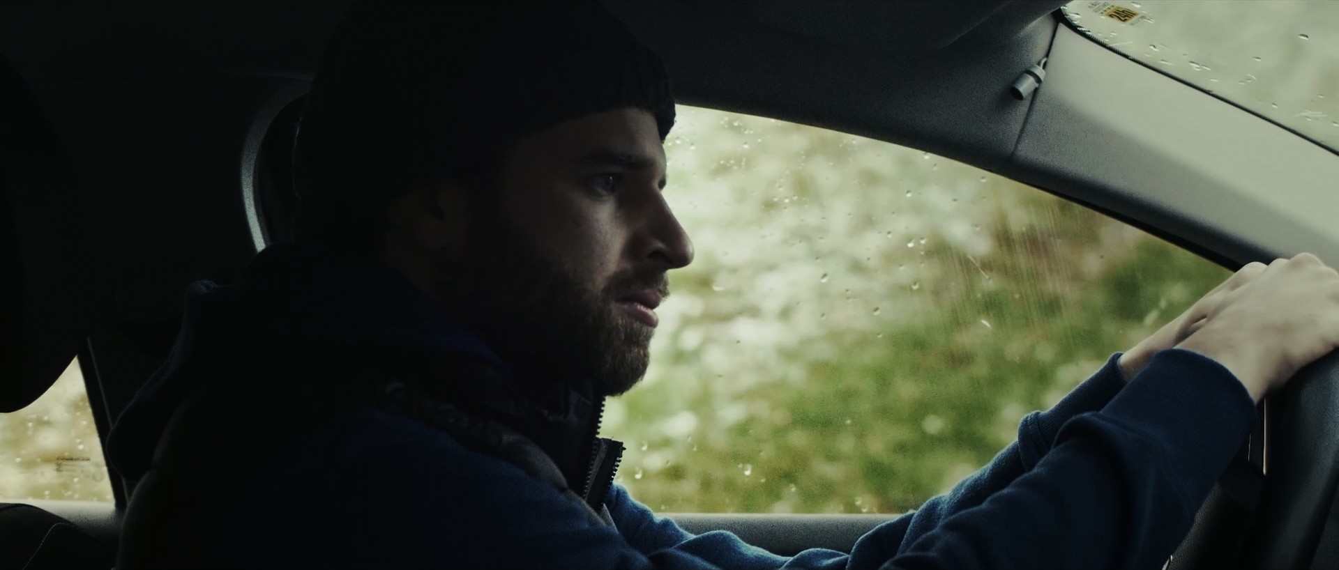 Cinematic profile shot of a man driving a car, reflection in the window.