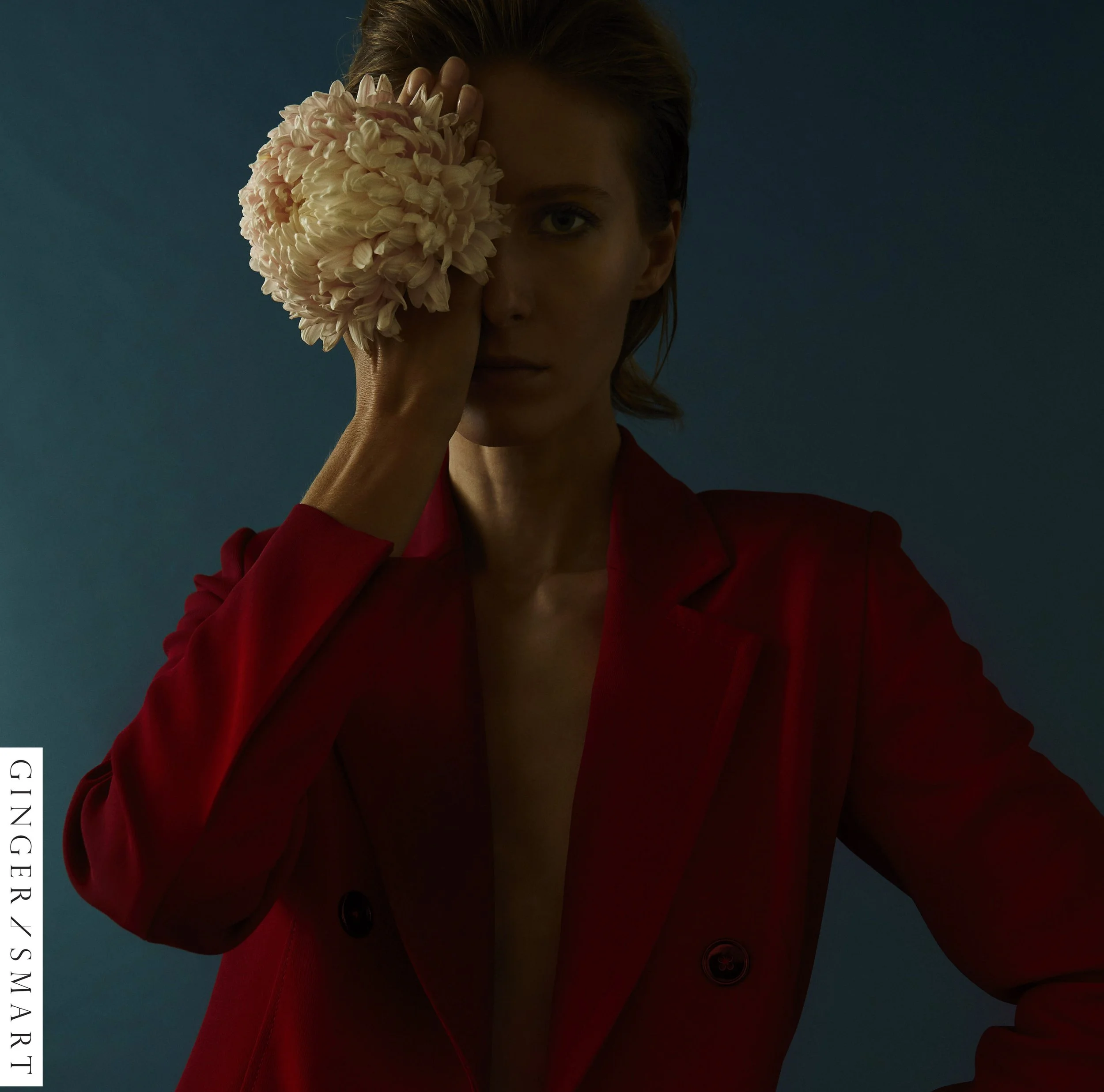 Model in a red jacket holding a white flower over her face