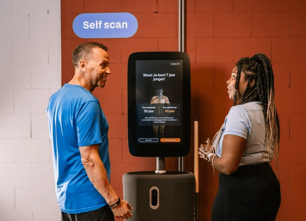 Two individuals are exercising in a hub, using fitness equipment with a focus on strength training.