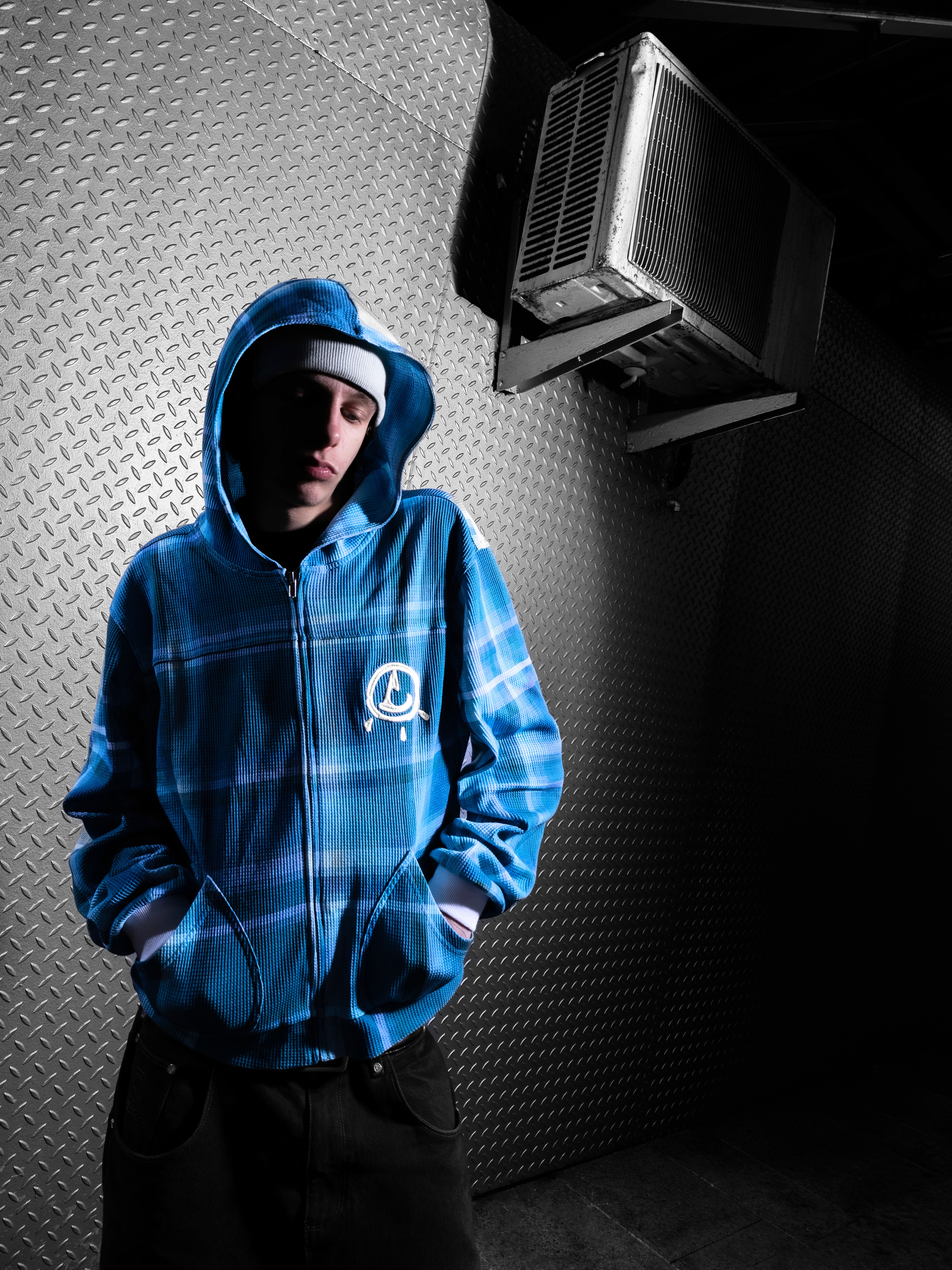 Man in a sporty jacket and light shorts walking across a football field, confidently pulling on his collar.