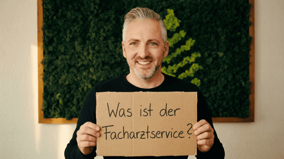 Hannes Weindorf mit einem Schild in der Hand, mit der Aufschrift: Was ist der Facharztservice?