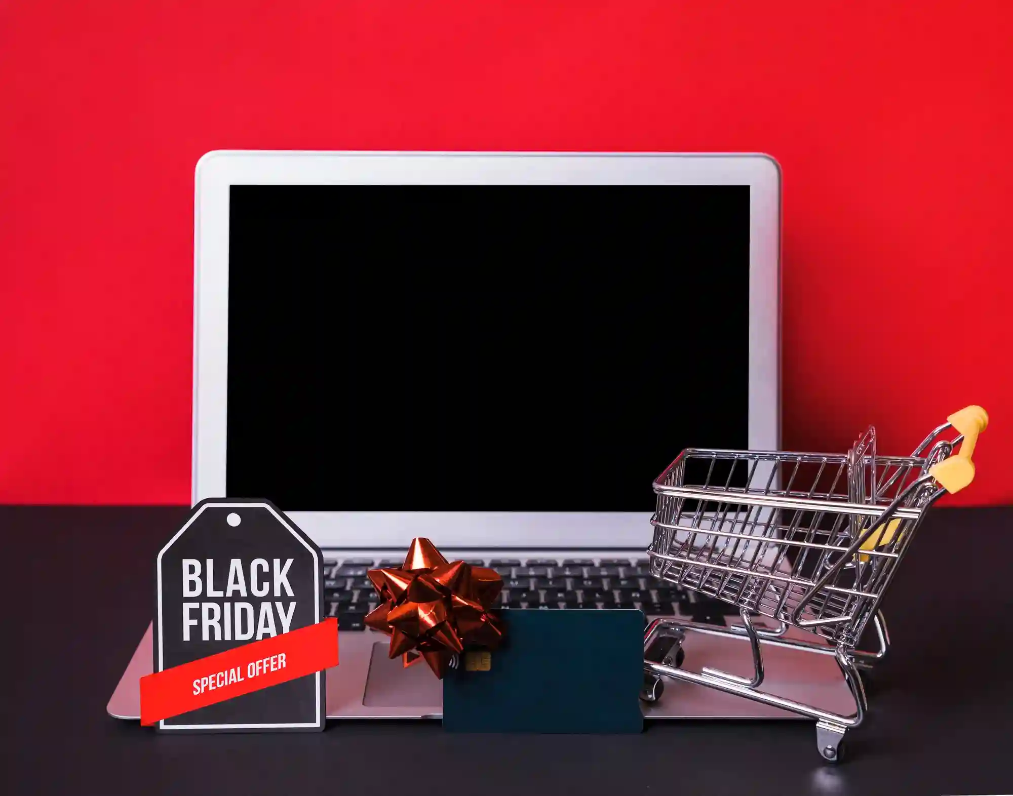 Black Friday shopping image with a laptop, miniature shopping cart, gift card, and a tag reading "Black Friday."