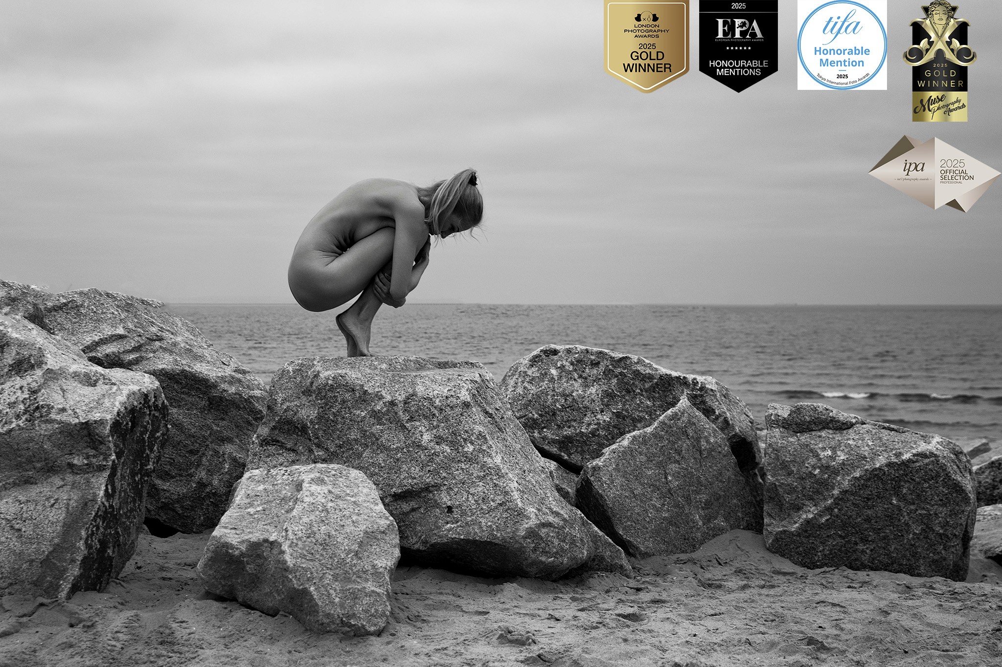 Agnieszka Czyzkowska fine art photography Warsaw woman crouching on rocks by the sea black and white stone and skin