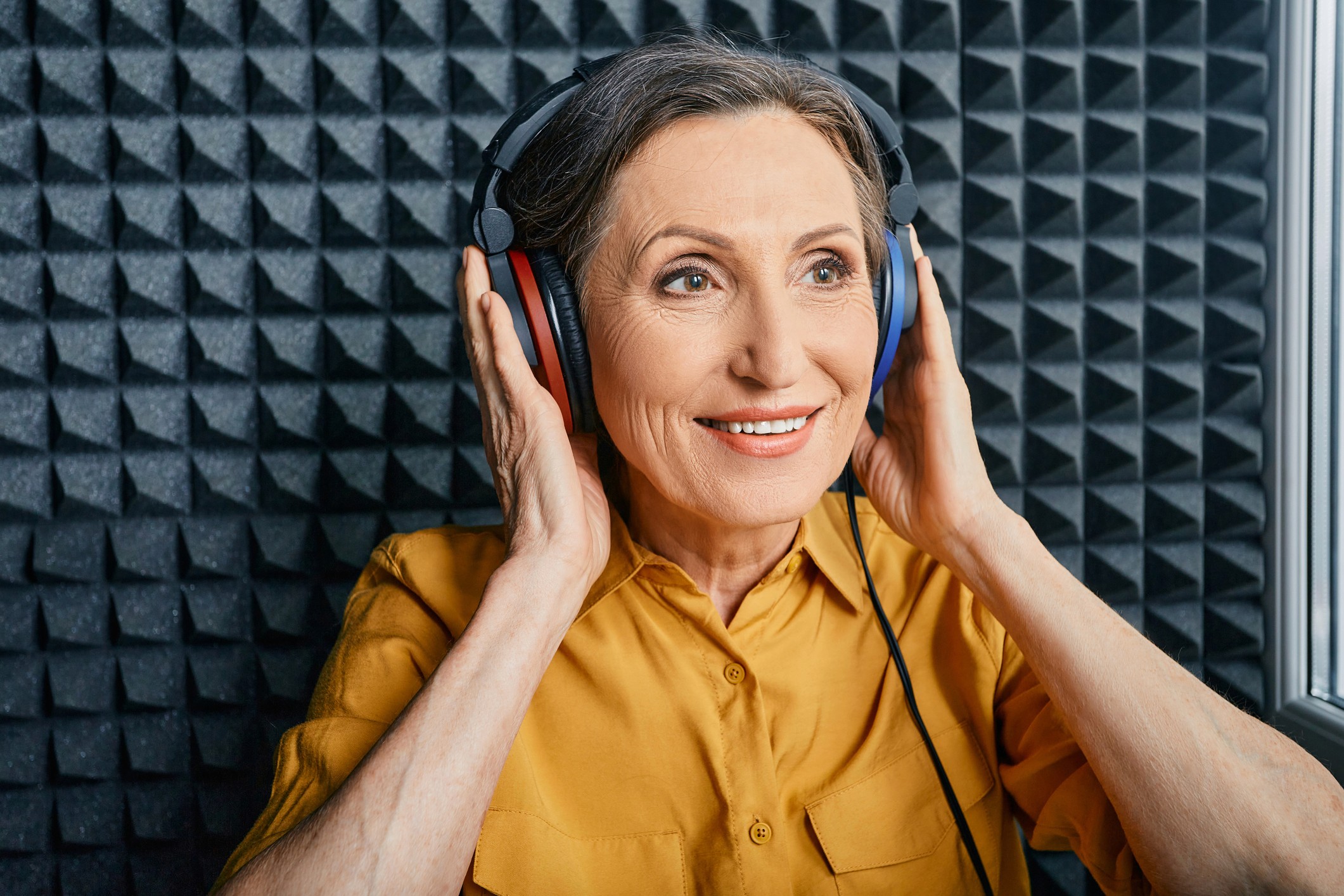 Mujer realizando una prueba auditiva con auriculares en una cabina insonorizada durante una evaluación audiológica