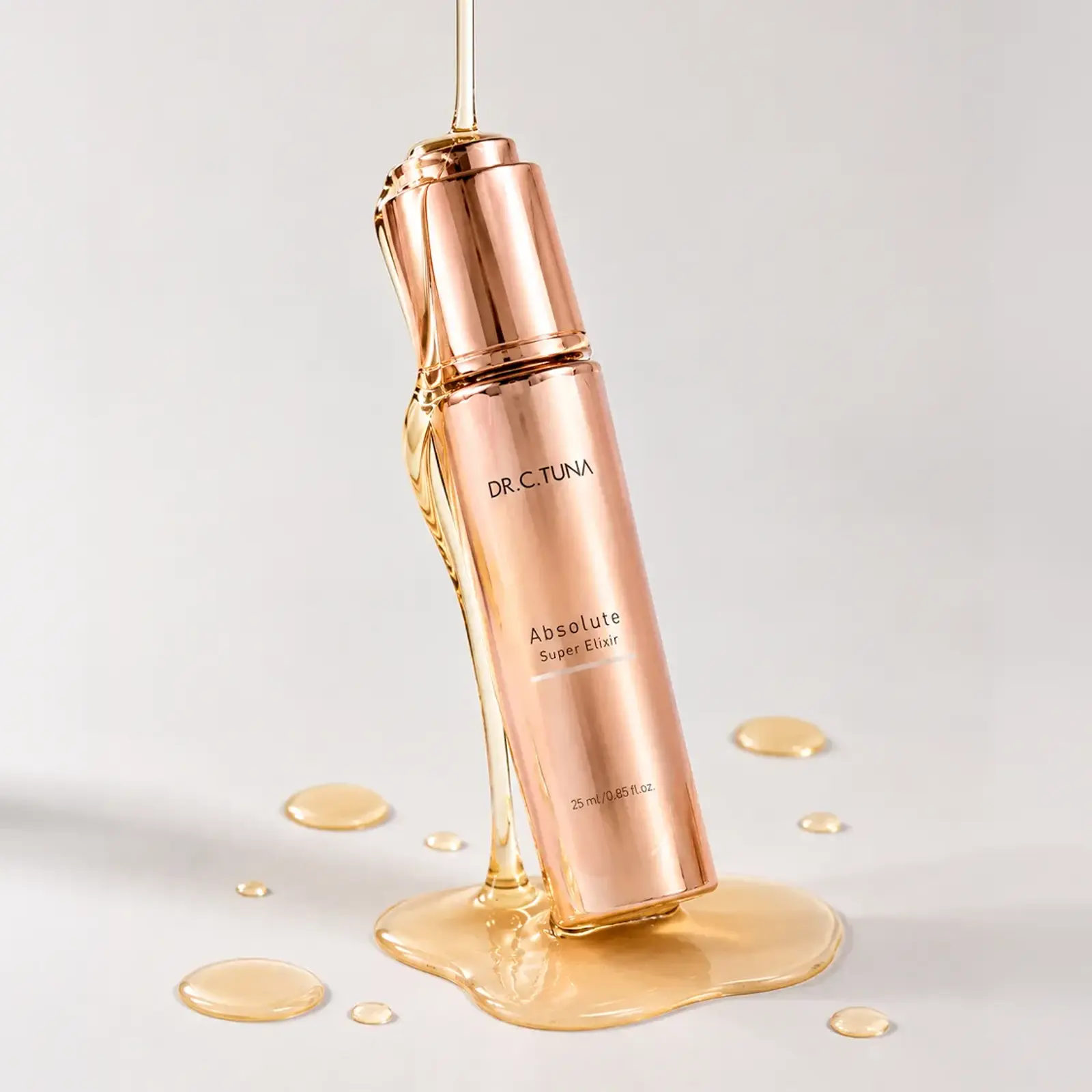 Frasco de Absolute Super Elixir entre gotas de aceite