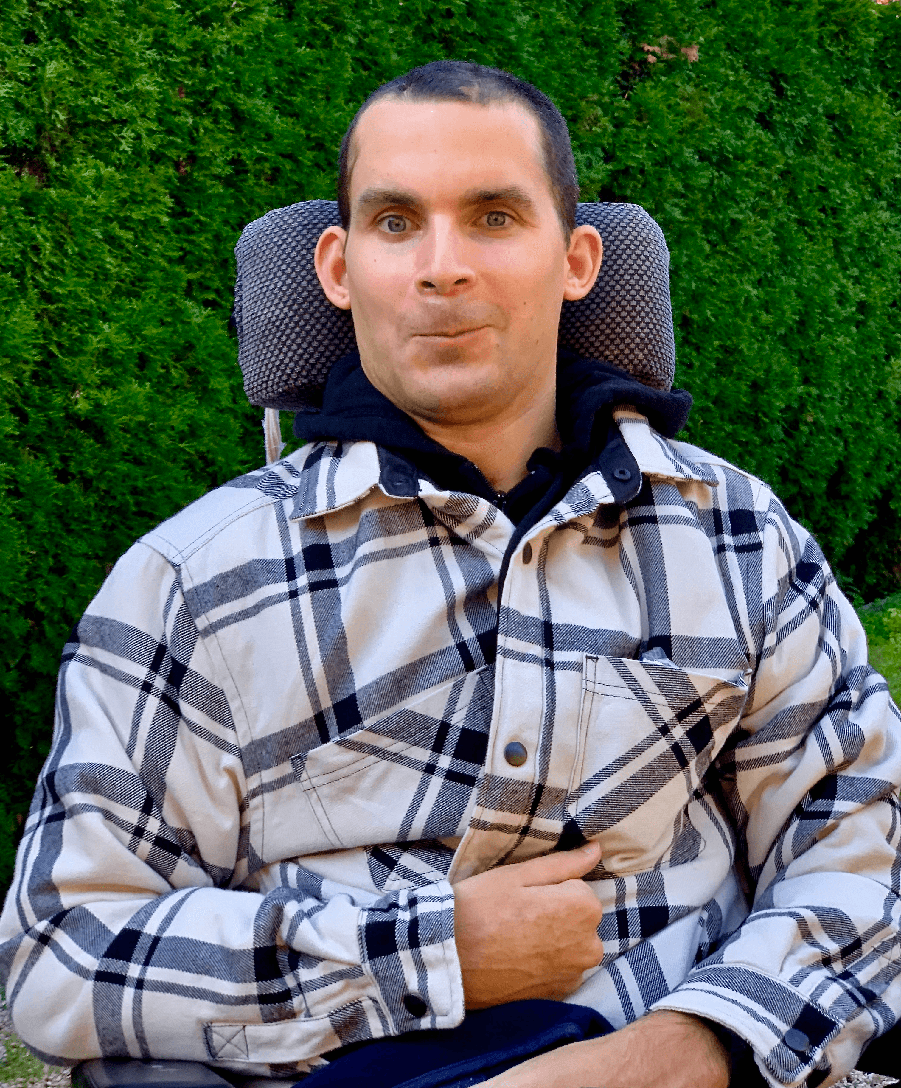 Ein junger Mann sitzt in einem Rollstuhl und blickt selbstbewusst in die Kamera.