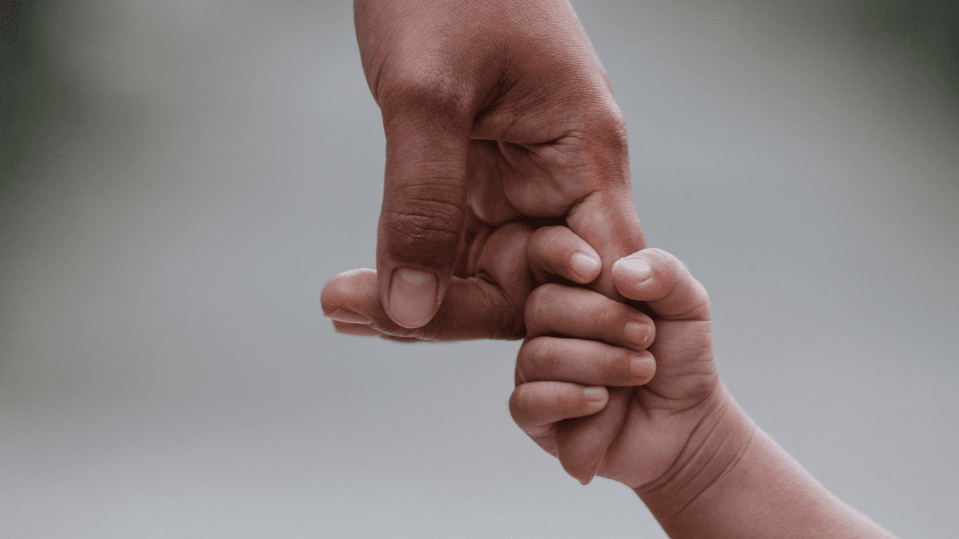 A softly lit hallway with a series of arched doorways, warm-toned walls, and wood flooring leading toward a seating area with neutral furniture.