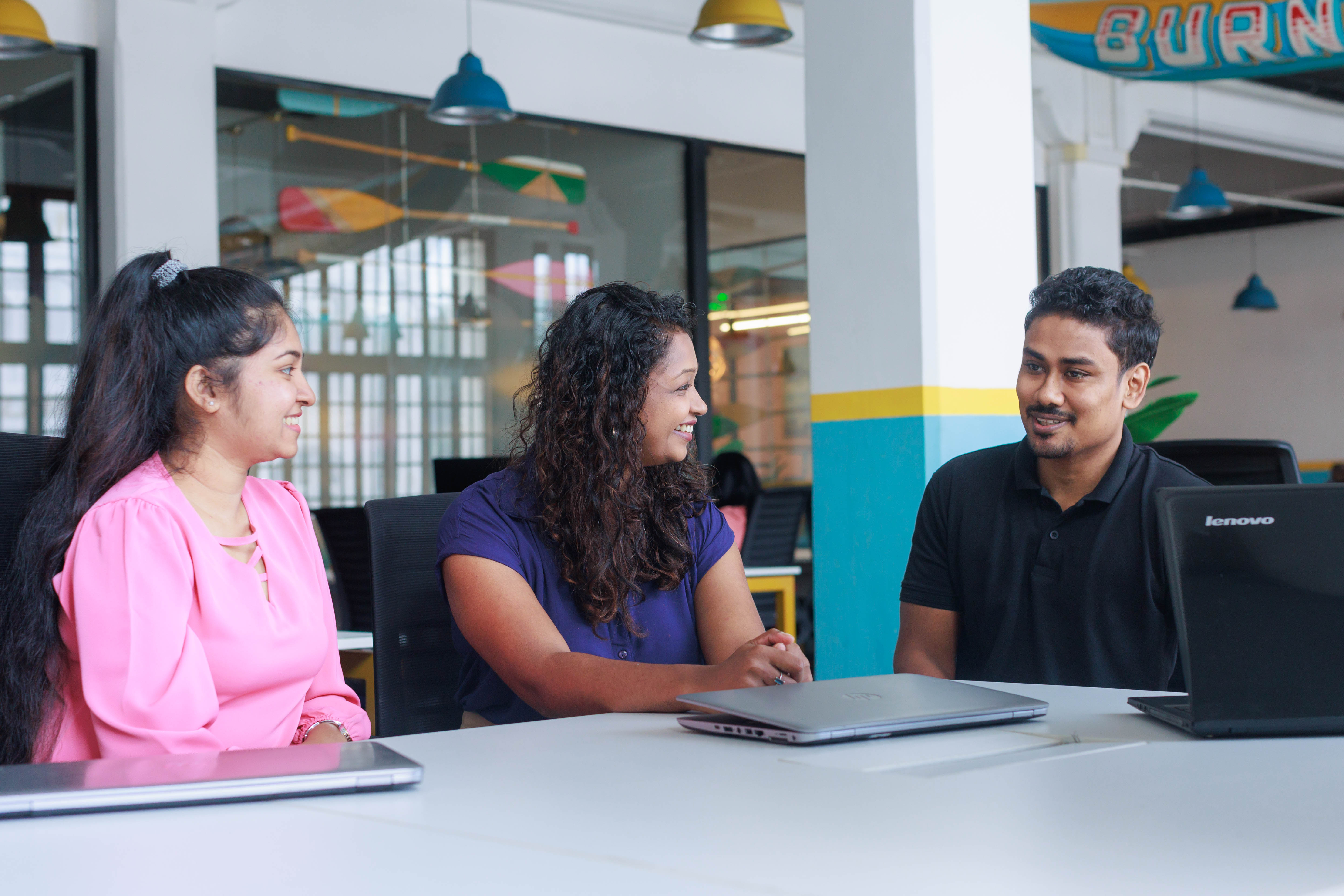 Three colleagues chatting around a table