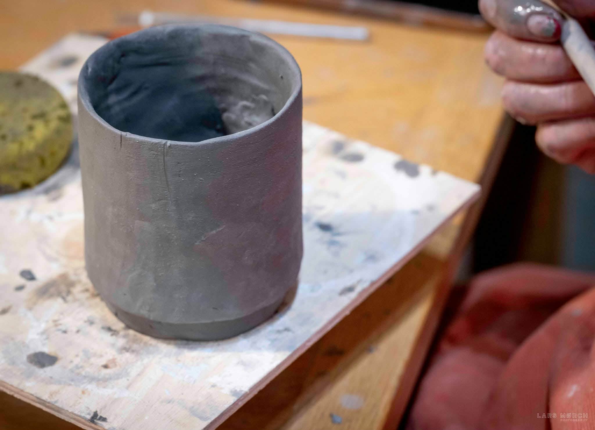 applying a thin layer of underglaze to a greenware cup