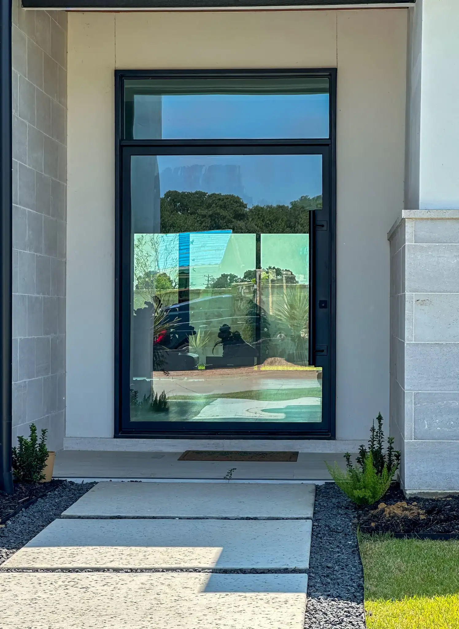 Modern steel pivot door with clear glass on a Southlake home