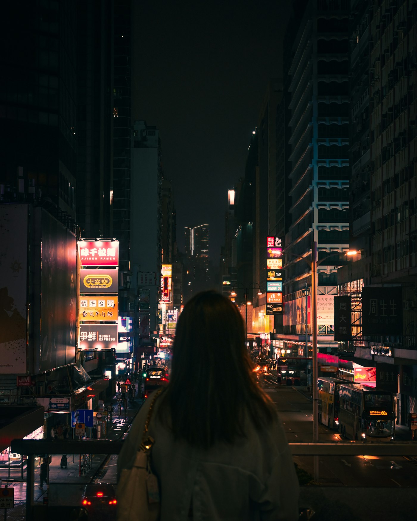 Woman looking out over a neon-lit city street at night