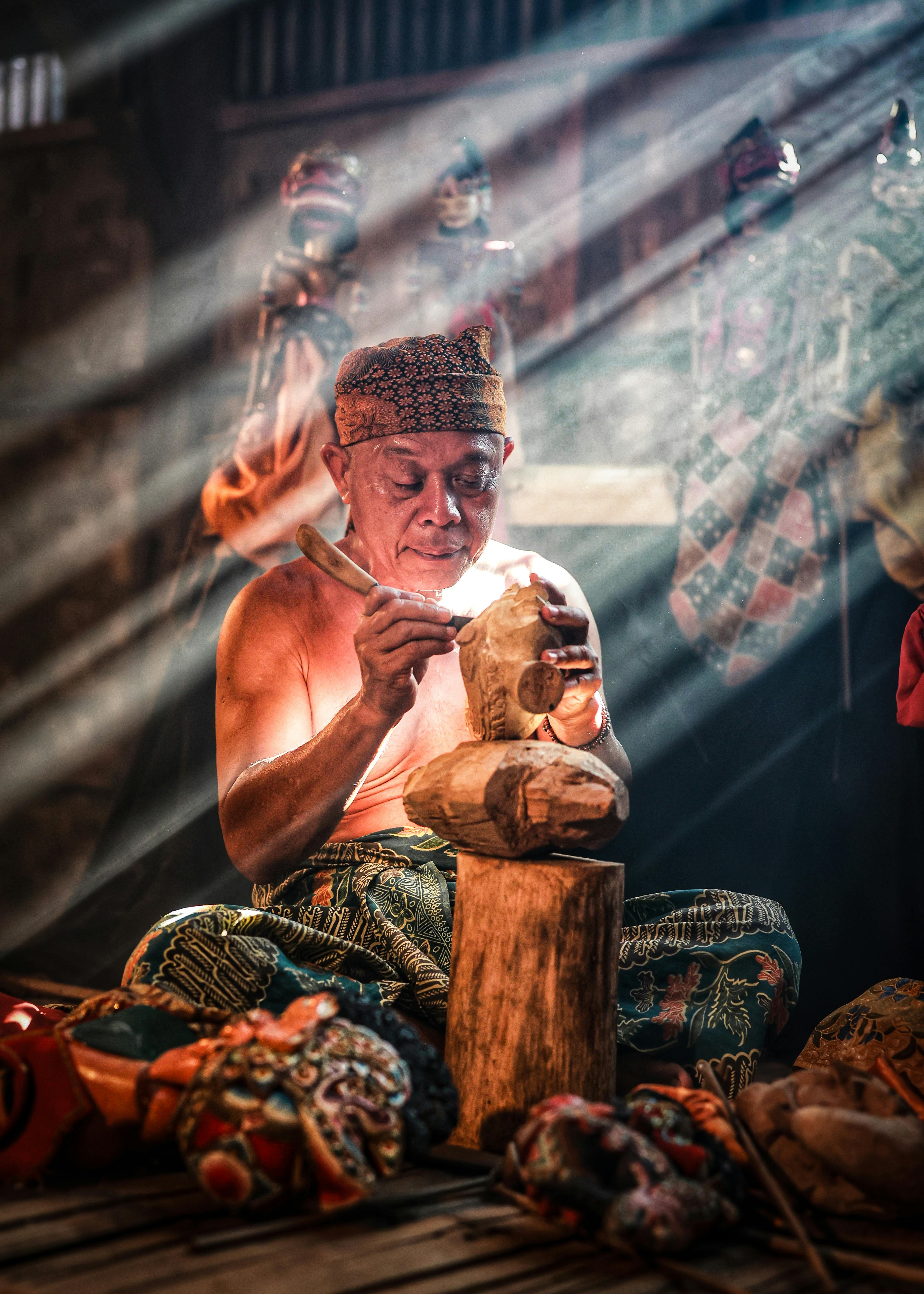 A skilled artisan in West Java intricately carves a traditional Javanese wooden puppet.