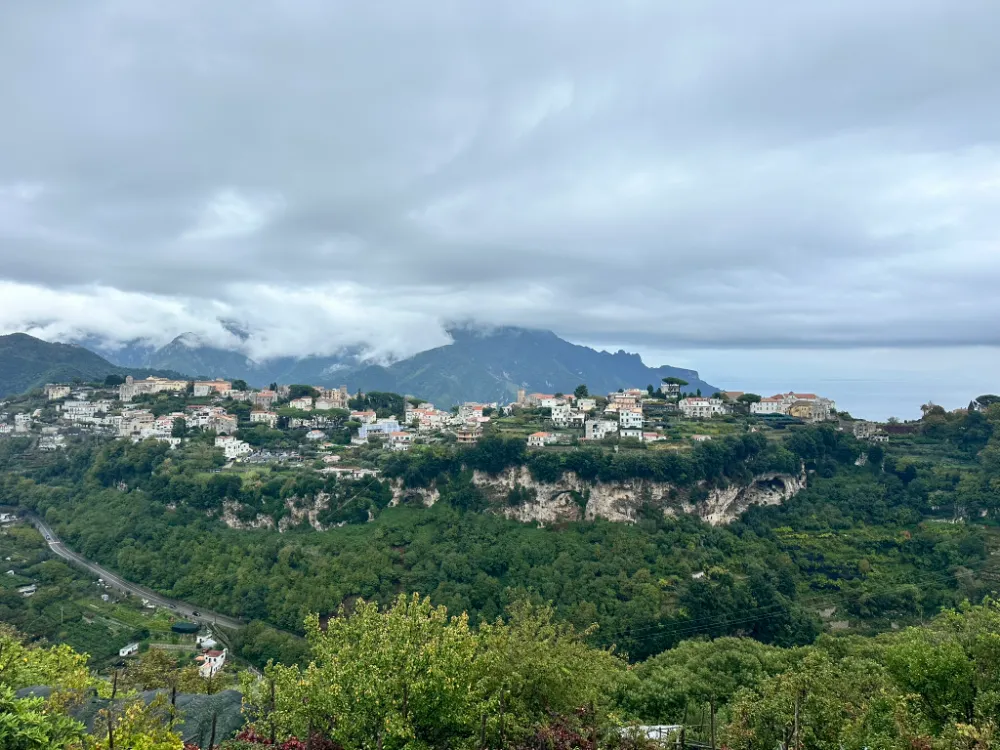 Villas scattered across the green hillside above Ravello, with cloud sitting on the mountains.