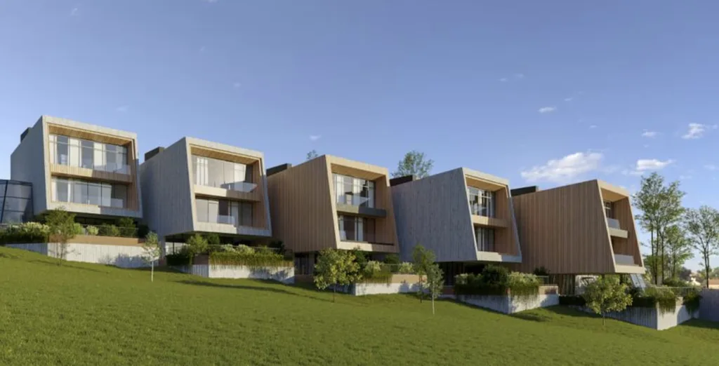 Row of minimalist wood-paneled homes with slanted rooftops and glass balconies on a grassy hill.