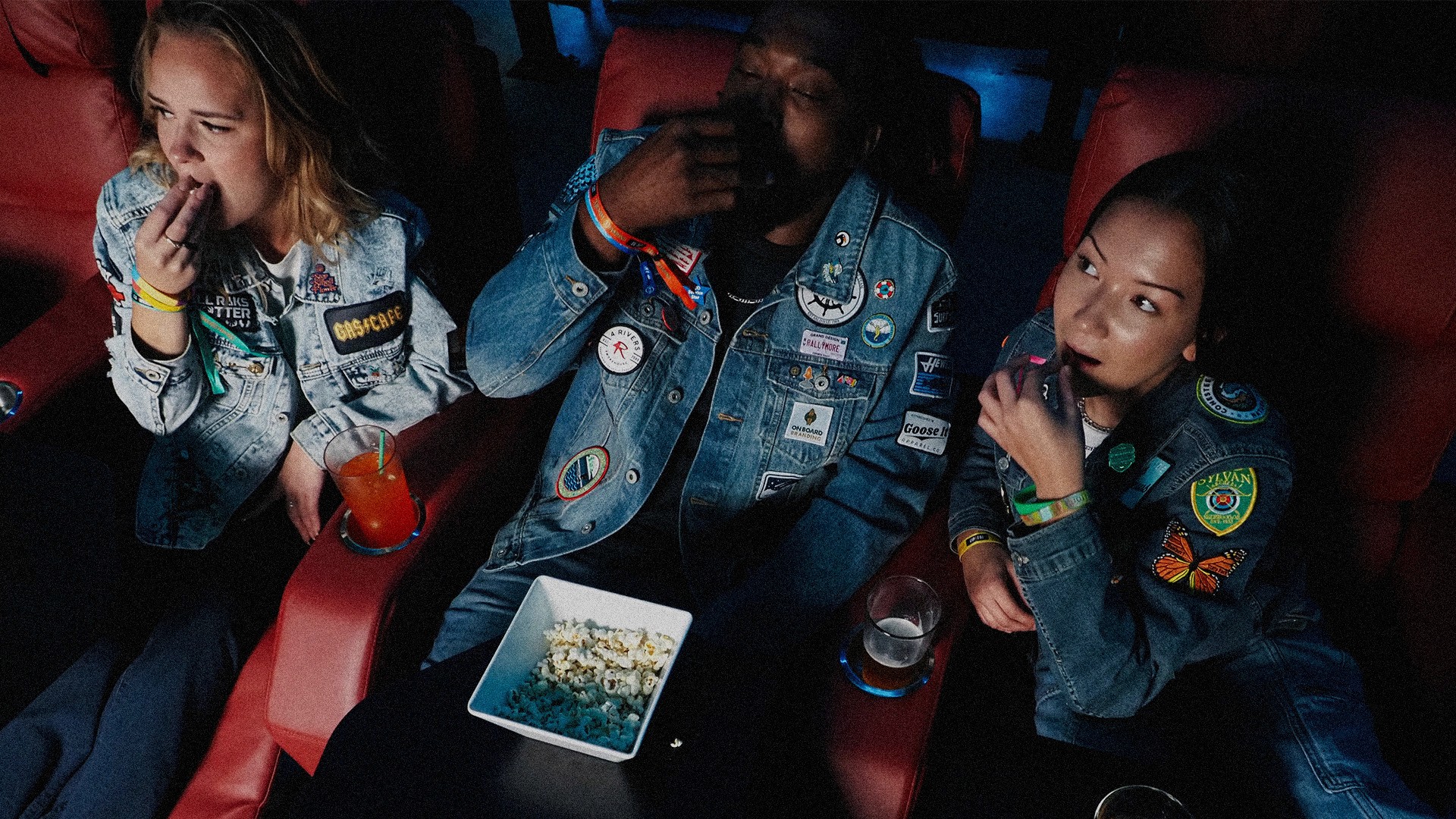 People eating popcorn in a movie theater wearing jackets with patches that cost less than 5 dollars to make.