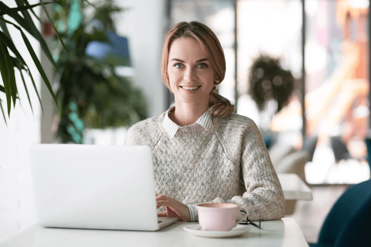 Woman working on a laptop in a café with a coffee cup, representing how Amazon sellers can win more Q4 sales with automation and less manual workload.