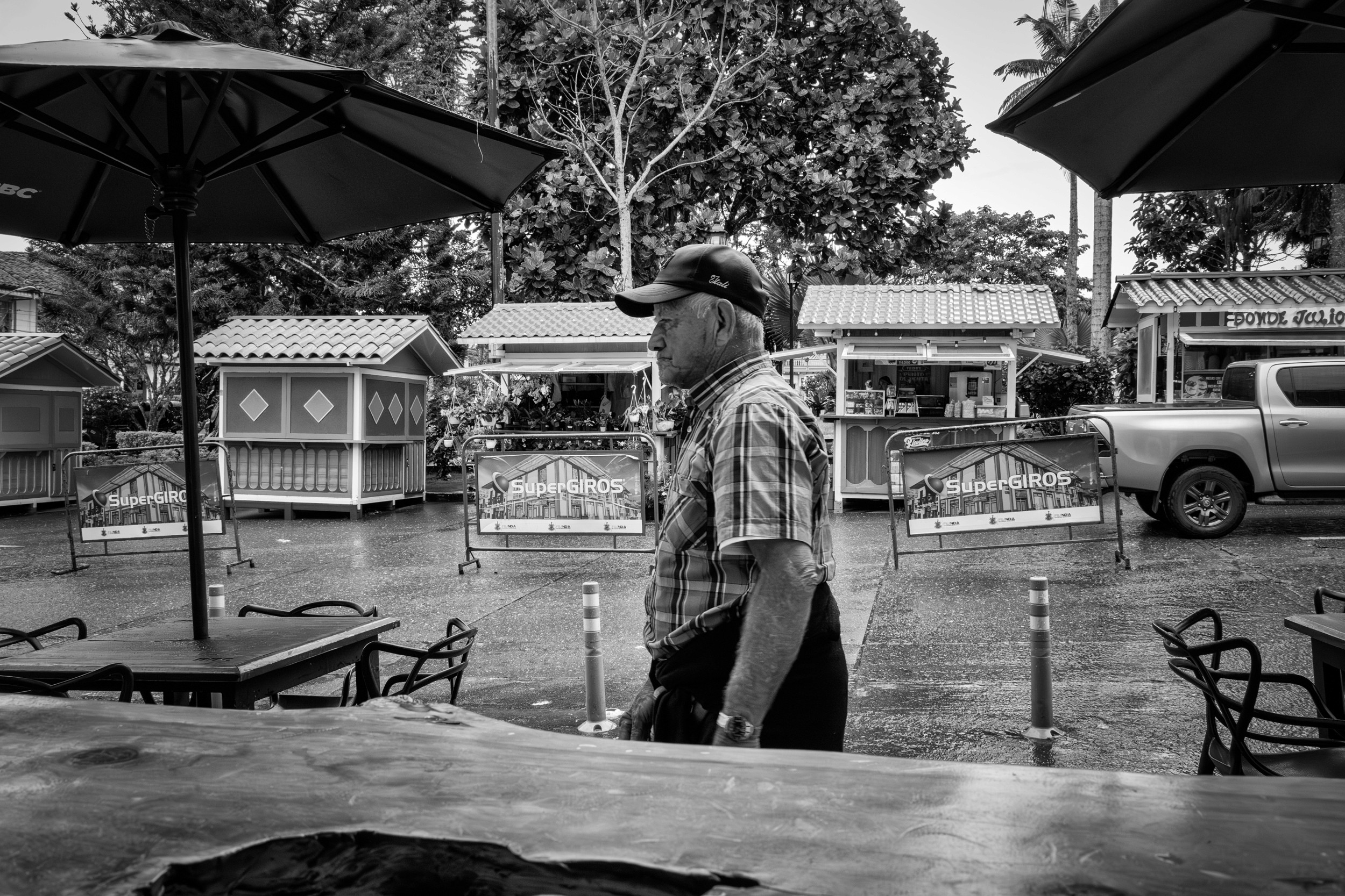 Rainy street scene with people passing by a bar window.