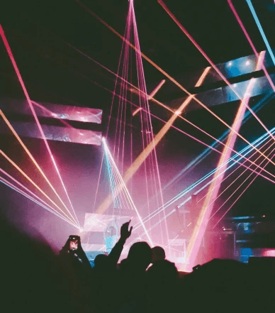 Pink and blue laser lights flashing during the concert as people dance