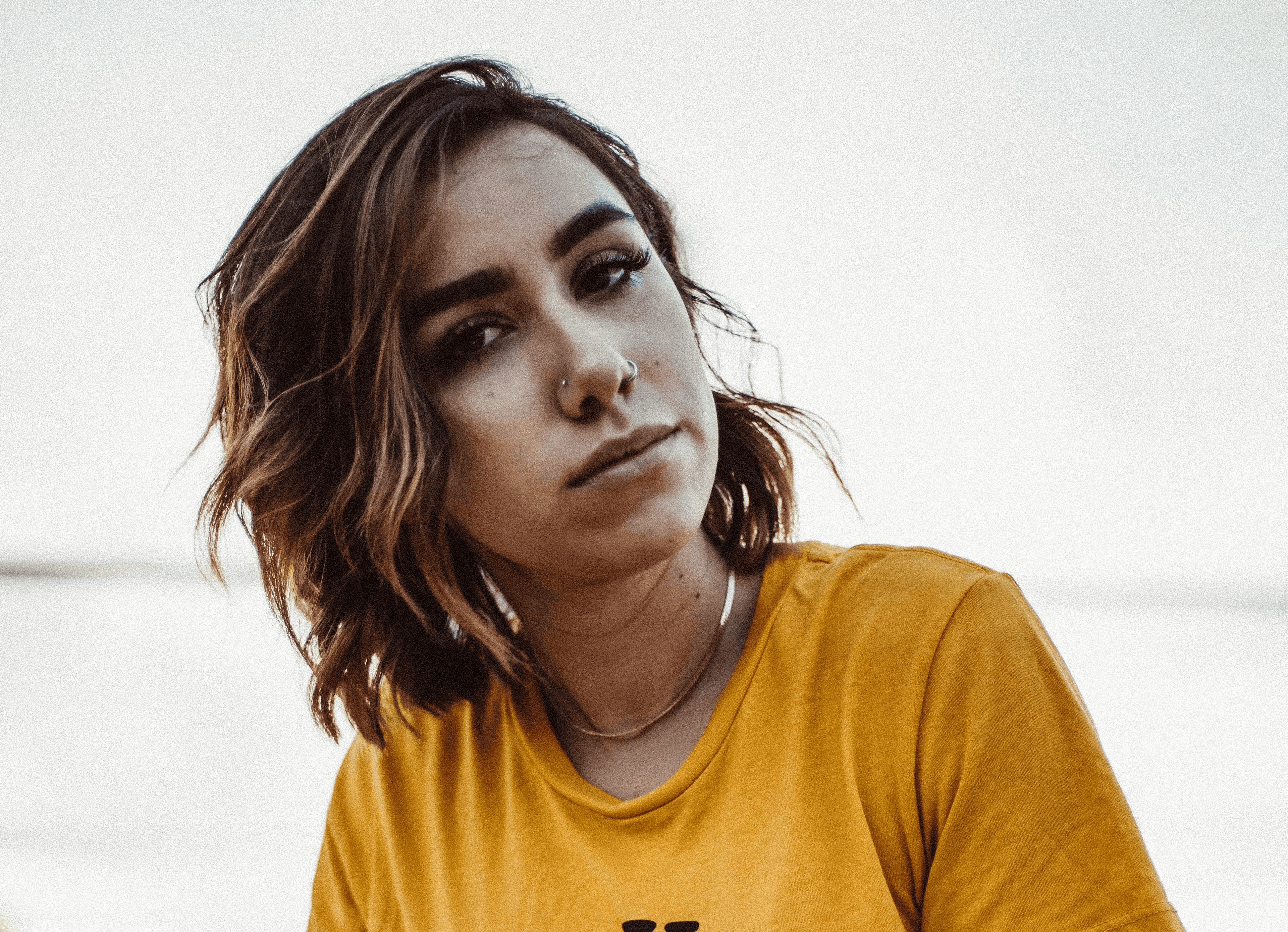 woman in yellow crew-neck shirt and blue short shorts sitting on bench