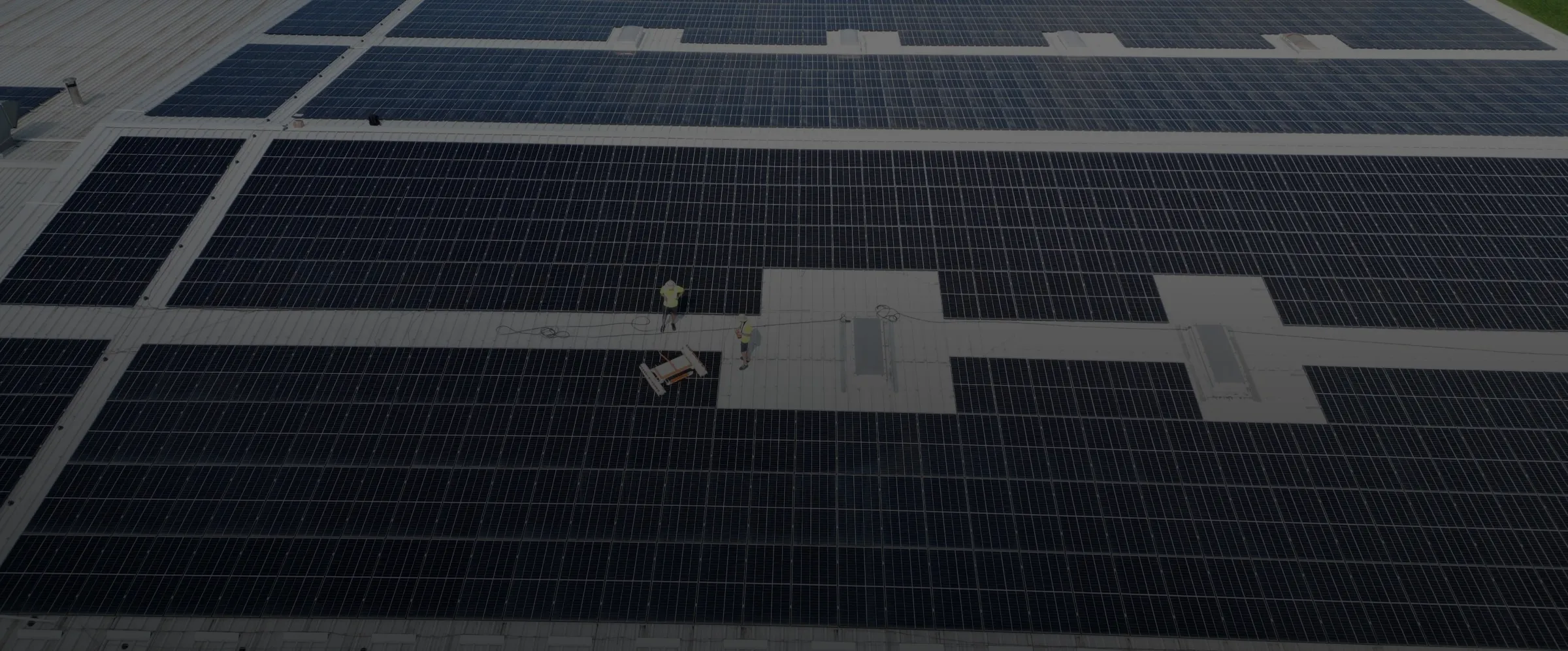 Vedere de sus cu doi tehnicieni SpalPanouri și robotul de curățare automată pe acoperișul unei hale