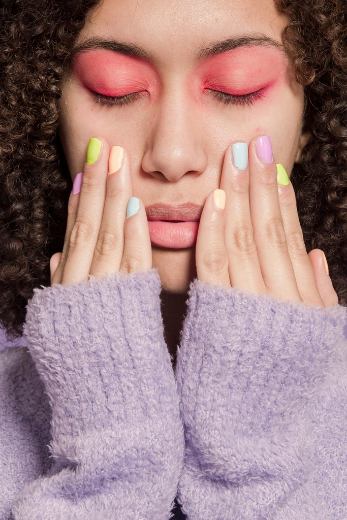 Woman with pastel rainbow nails and bold pink eyeshadow