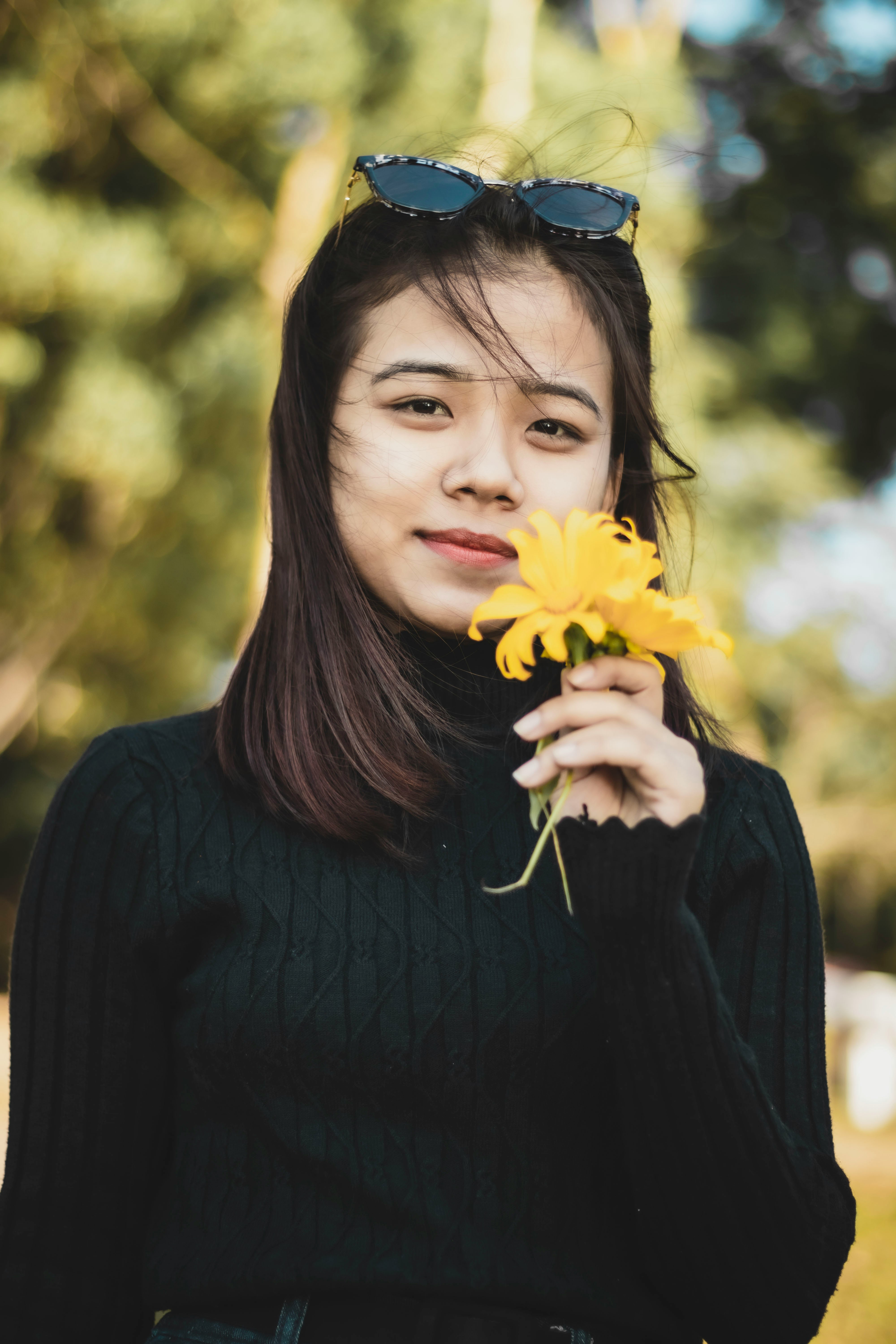 woman in black long sleeve shirt holding yellow flower