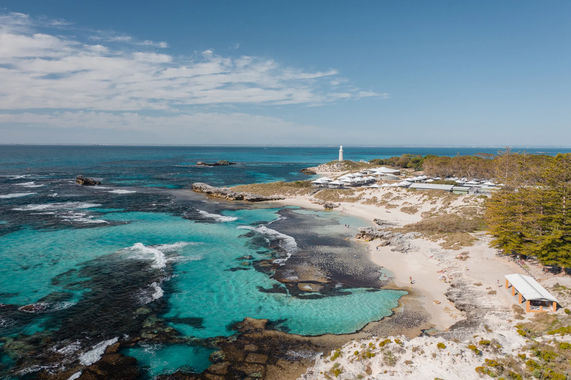 Aerial of a lighthouse point above turquoise reef pools and low scrub