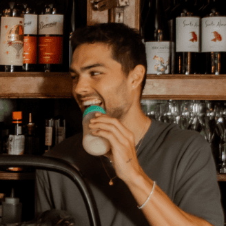 A person drinking from a drink glass in an empty bar.
