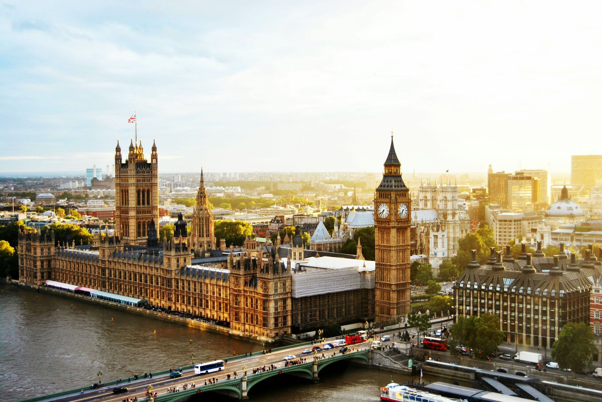 Panoramic view of the Houses of Parliament and Big Ben in London, captured during sunset with the River Thames and Westminster Bridge in the foreground, showcasing the iconic British architecture and city skyline.
