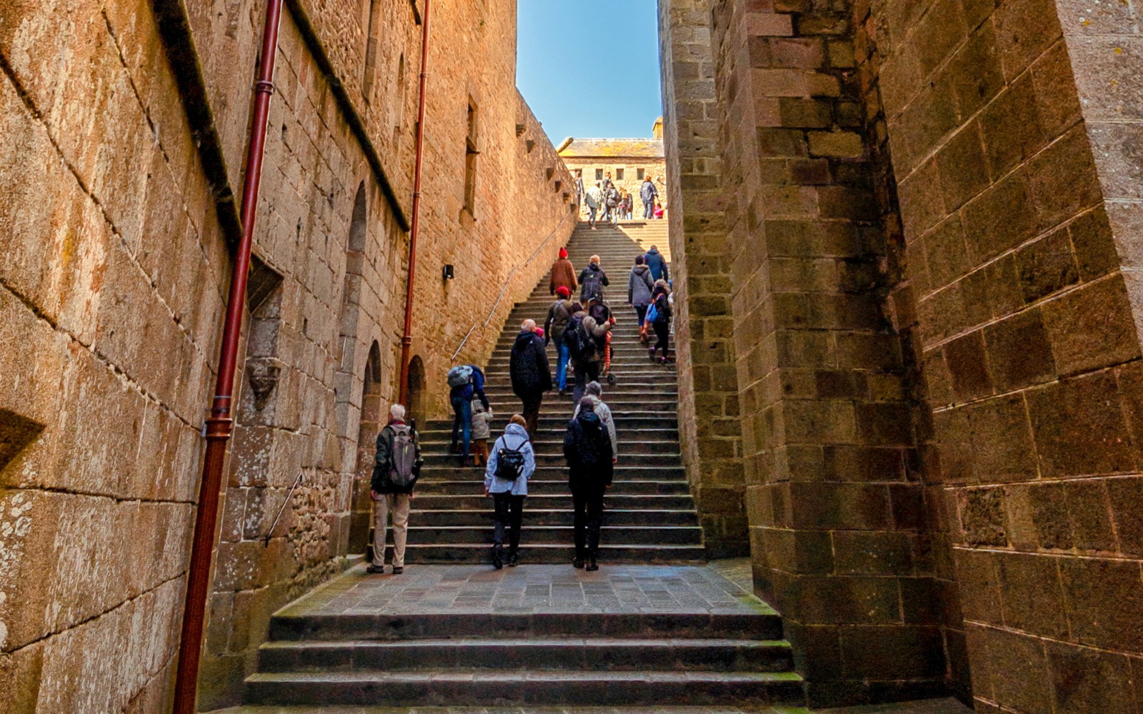 Tourists ascending stone steps in Mont Saint Michel, France.