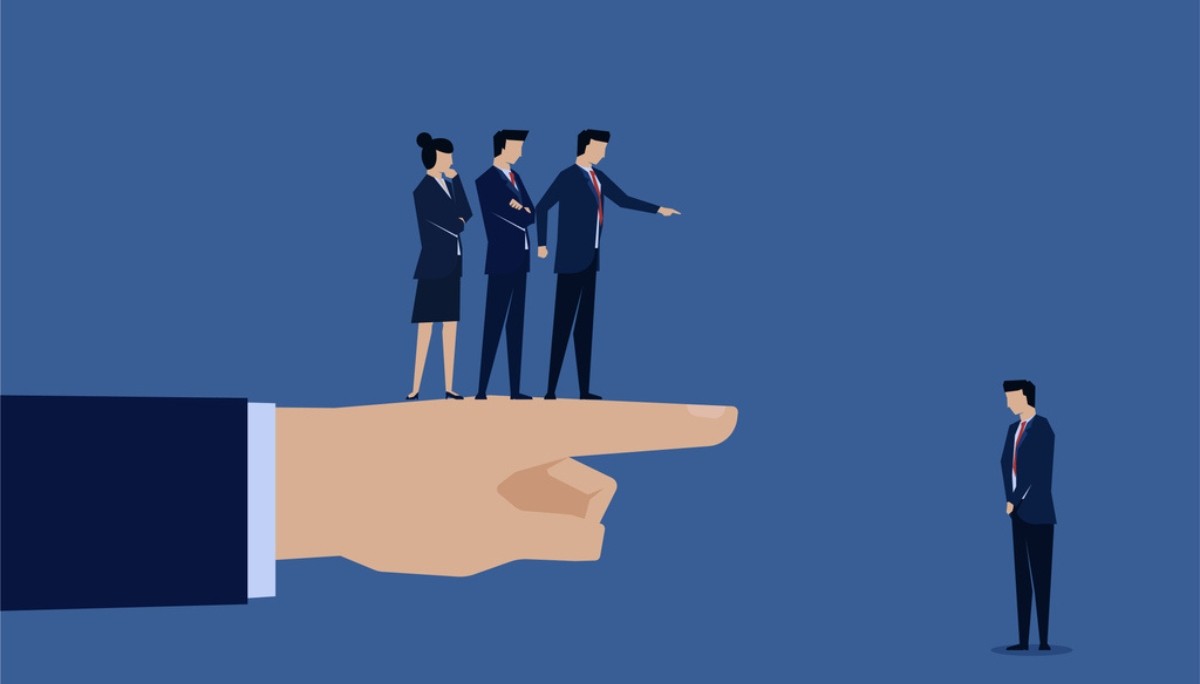 Illustration of a large hand pointing toward a solitary professional while others stand together on the hand’s finger—symbolizing workplace judgment, accountability, and the challenge of owning up to mistakes in a team environment.