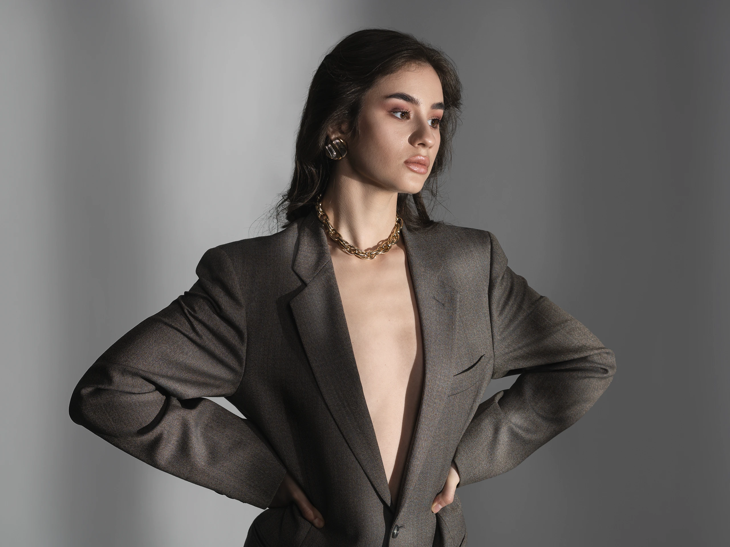 Editorial fashion portrait of a woman wearing an oversized blazer in a minimalist studio.