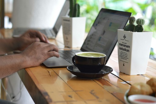 Person working on a laptop with a cup of tea, illustrating the digital nomads