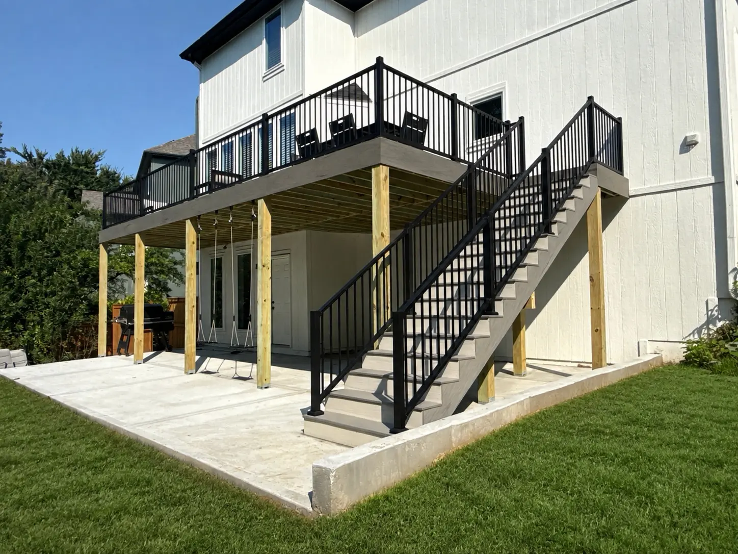 White house with a grey deck and black railing.