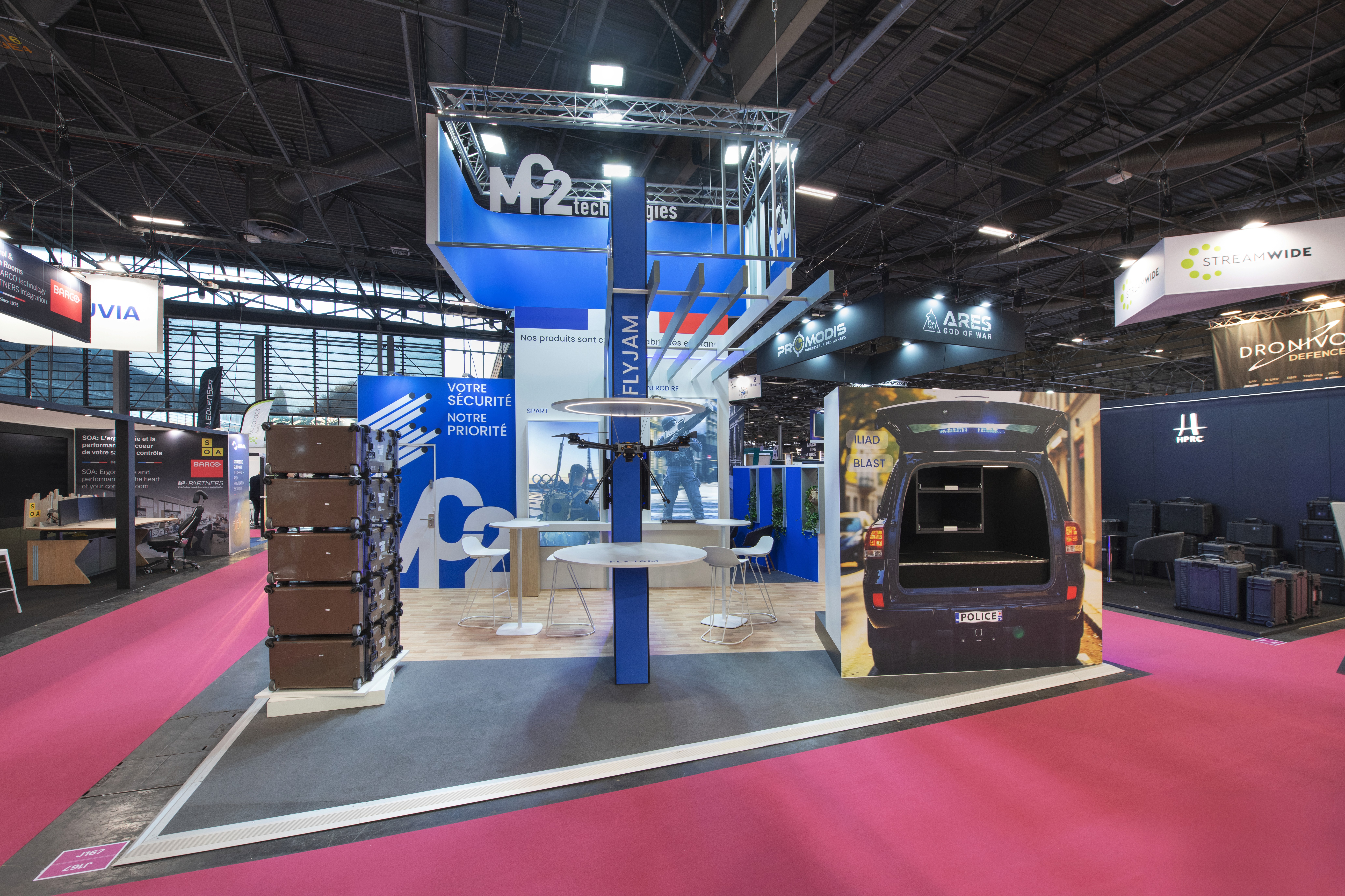 Stand MC2 Technologies Milipol Paris 2025 – vue d'ensemble scénographie ouverte avec exposition équipements sécurité, conception Expace