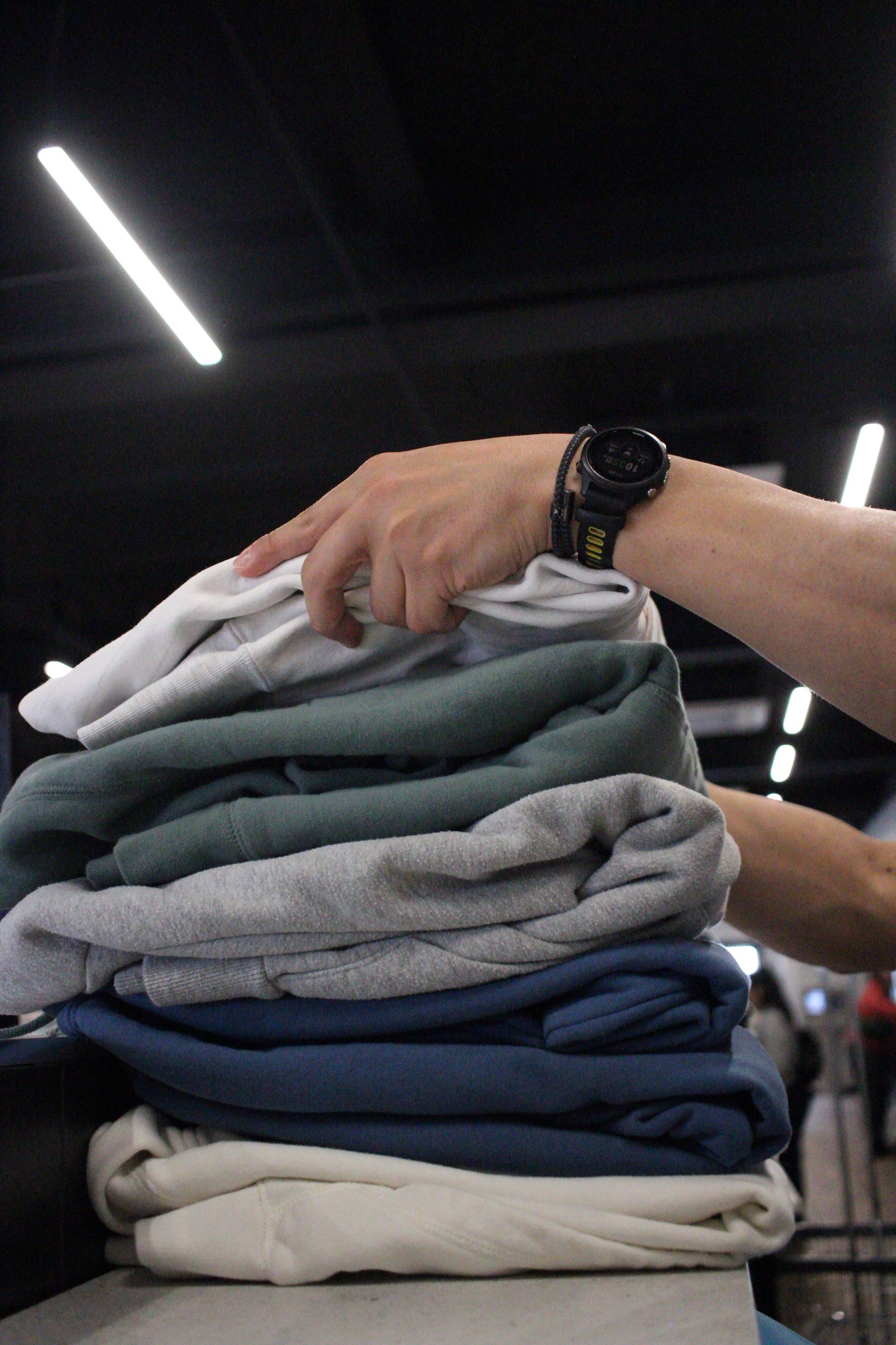 Hands folding stacks of clean clothes, showcasing efficient laundromat operations that drive high profit margins.