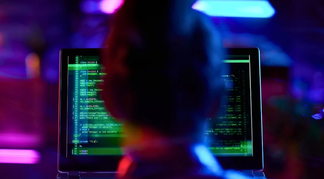 Person arbeitet am Computer mit Quellcode – IT-Sicherheit im Mittelstand