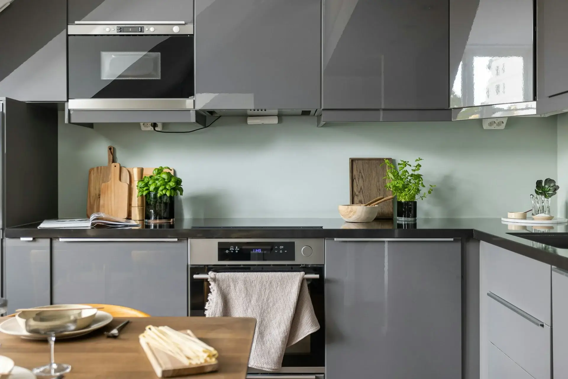 Modern gray kitchen with sleek cabinets, built-in oven, and wooden accents.