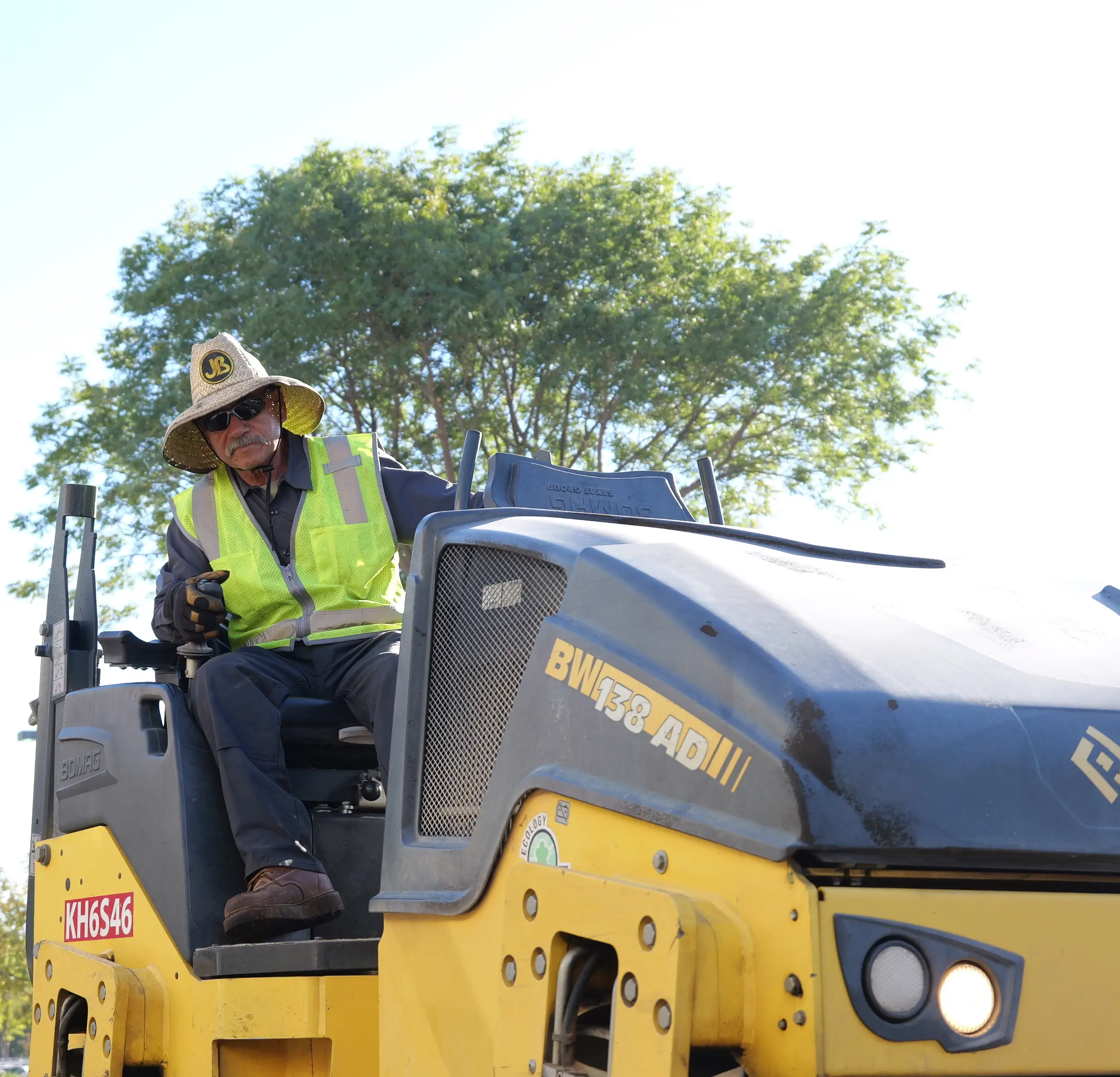 Roller operator compacting new asphalt pavement on project