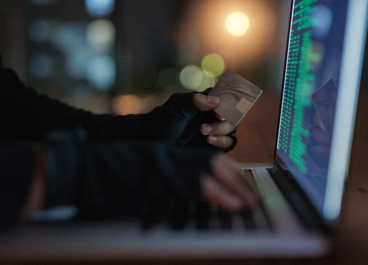 mão com luvas pretas segurando cartão de crédito em frente a tela do notebook