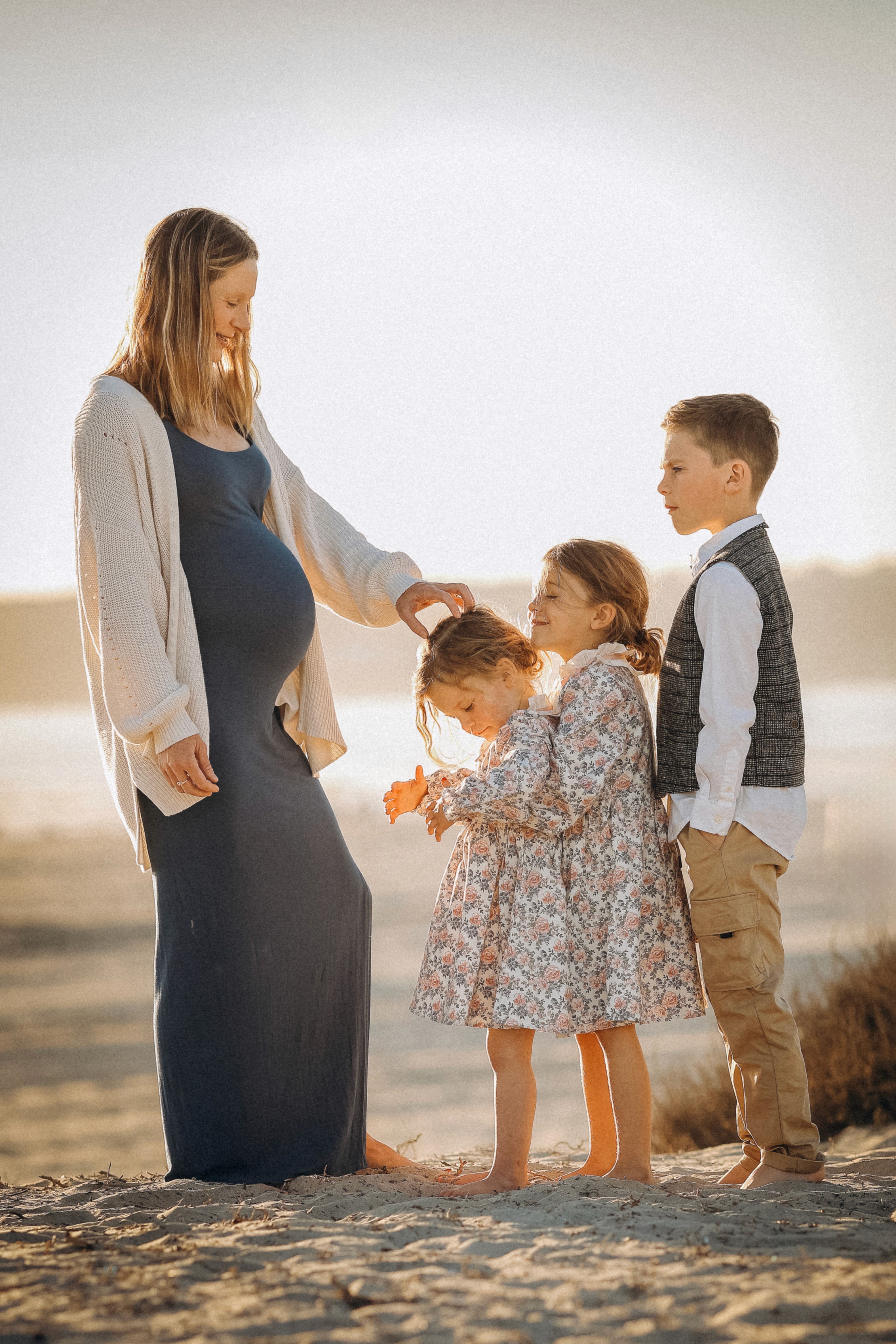 Mother holding hands with her kids during a calm sunset session at the beach.